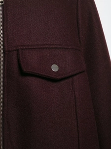 Detailed close-up of wine red wool-like fabric texture and metal zipper on short jacket