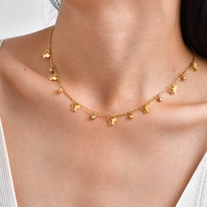 Elegante goldene Kleeblatt-Schmetterlingshalskette mit Zirkonia am Hals einer Frau