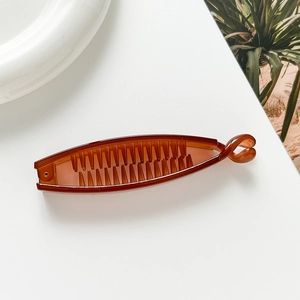 Detailed close-up of a glossy amber plastic banana hair clip on a minimalist white surface