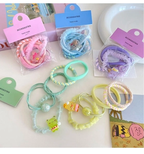 Close-up of macaron color flower hair ties with cute cartoon pendants in gift packaging