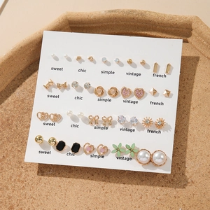 15 pairs of vintage gold earrings set with pearls and rhinestones on a cork tray