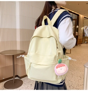 Detailansicht eines beige Nylon-Rucksacks mit rosa Plüsch-Anhänger in Shop-Umgebung