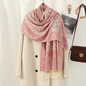 Pink paisley jacquard scarf with fringe trim styled over a beige coat for a retro look