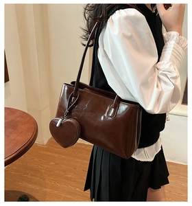 Detail of dark brown vintage tote bag with heart-shaped pouch worn on a shoulder