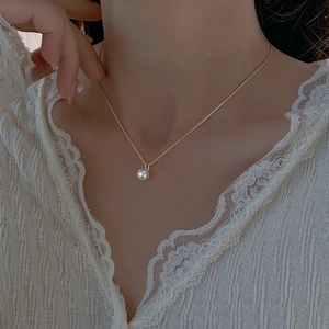 Elegant gold chain necklace with round white pearl pendant for women on a model