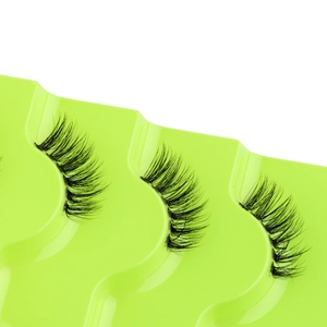 Close-up of thick curly black half eyelashes on a green wavy tray for a natural eye lift