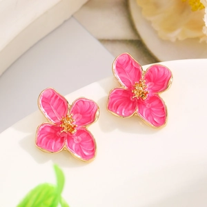 Macro view of pink enamel flower earrings with golden alloy petals and textured center