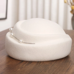 Détail d'un béret blanc en laine feutrée avec perles élégantes et strass brillants