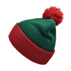 Detail of red pompom and forest green knitted texture on a Christmas beanie hat