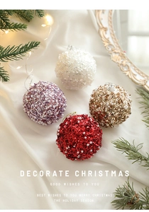Detailed view of sequined Christmas baubles in red gold and white on fabric