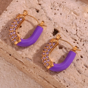 Macro shot of U-shaped gold plated earrings with purple enamel and pavé zircons