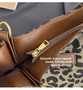 Close-up of leopard canvas tote with golden metal zipper and brown leather trim detailing