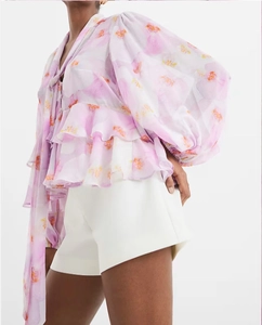 Detail of layered ruffles and sheer floral chiffon fabric on a purple long sleeve blouse