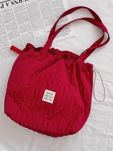Sac fourre-tout rouge à cordon avec texture plissée verticale et étiquette SOZAKKA sur tissu