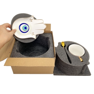 Unboxing detail of ceramic Hamsa hand saucer with evil eye pattern and gold-rimmed cup