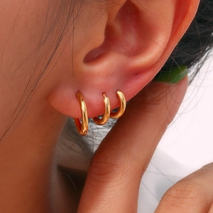 Detailed macro view of three 18K gold-plated stainless steel hoop earrings on model ear