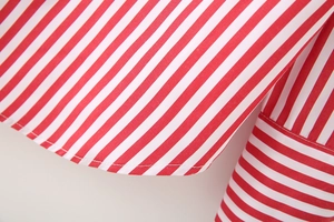 Close-up of the red and white striped poplin shirt showing fine stitching on the cuff