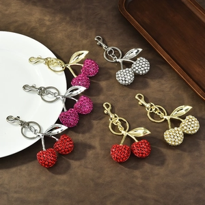 Sparkling crystal cherry keychains in red, pink, gold and silver on a dark wooden table