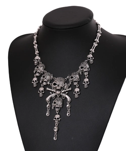 Close-up of gothic skull and pistol pendants on silver metallic tassel necklace