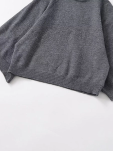 Detail of dark grey knit sweater showing high-quality fabric texture and ribbed hem