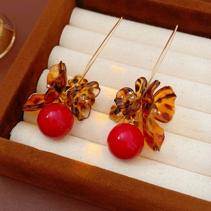 Detail of flower earrings with red beads and amber petals on a jewelry box cushion