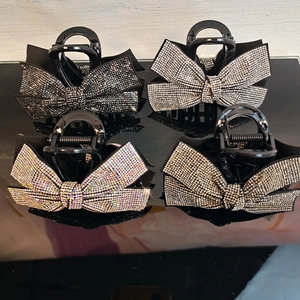 Detailed view of four bow-shaped rhinestone hair claws in black, silver, and gold colors