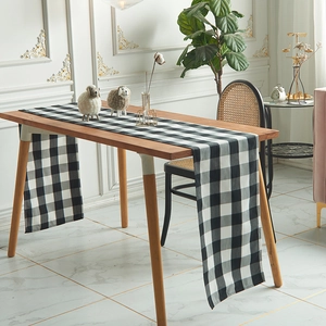 Minimalist Nordic black and white plaid table runner draped on a wooden dining table