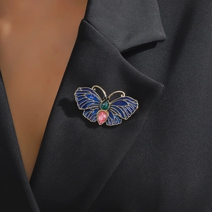 Broche papillon vintage dorée avec émail bleu et gemmes sur le revers d'un tailleur