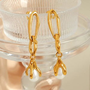 Creative gold chain drop earrings with imitation pearls hanging on a glass rim