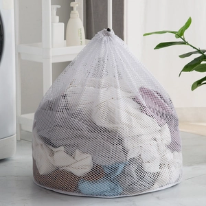 White fine mesh laundry bag with drawstring closure in a modern laundry room setting