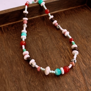 Dettaglio ravvicinato della collana di pietre colorate su un vassoio di legno rustico