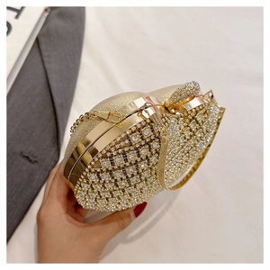 Golden heart-shaped evening clutch bag with rhinestones held by a model in a gray suit