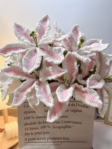 Close-up of handmade pink and white crocheted lily bouquet in a decorative paper bag