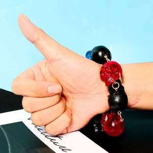 Dunkles Totenkopf-Armband mit schwarzen Perlen und roten Totenköpfen am Handgelenk