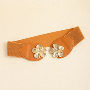 Close-up of golden metal flower buckle on orange-brown elastic waist belt for women