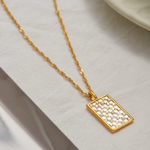 Détail d'un pendentif rectangulaire en acier inoxydable doré 18 carats avec zircons blancs