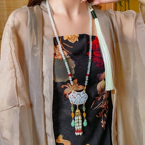 Detail of beaded necklace featuring a carved jade pendant with colorful tassels and beads