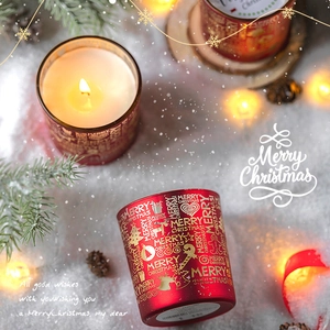 Weihnachtsduftkerze im roten Glas mit goldenem Tannenbaum und festlicher warmer Beleuchtung