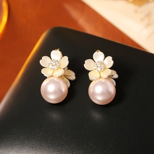 Detail of elegant shell flower earrings with pink pearls and zircon stones on black leather