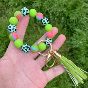 Silicone beaded keychain bracelet with green tassel and marble beads held outdoors