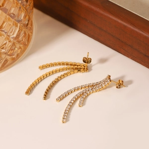 Detailed macro view of gold tassel earrings with zircon inlay on a wooden display