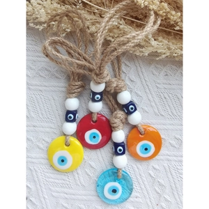 Detail of four colorful handmade evil eye hanging ornaments with rustic jute ropes