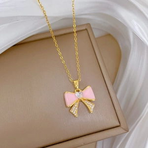 Macro detail of gold necklace with pink bow pendant and shimmering heart cubic zirconia