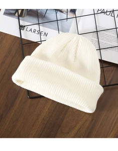 Detailed view of cream white knitted beanie on black metal rack over wood background