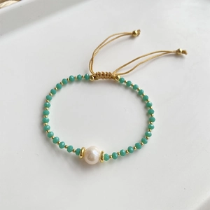 Detail of bohemian handmade bracelet with white freshwater pearl and green crystals