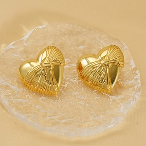 Golden heart stud earrings with woven texture on elegant satin background