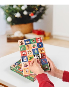 Detail showing hands opening the 16th compartment of a 24-day Christmas advent calendar box