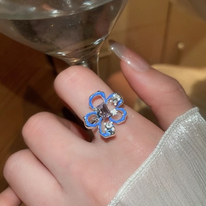 Dettaglio anello a fiore in smalto blu, pietra viola e zirconi su una mano