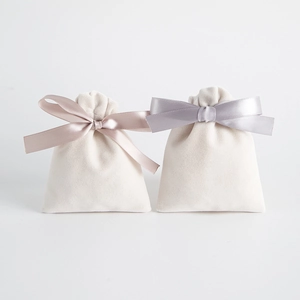 Elegant cream velvet jewelry pouches with satin drawstrings and decorative bows