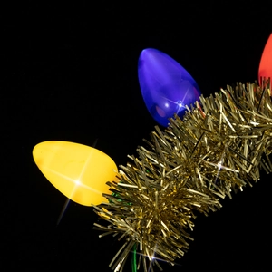 Close-up of glowing LED Christmas bulb headband with colorful lights and gold tinsel